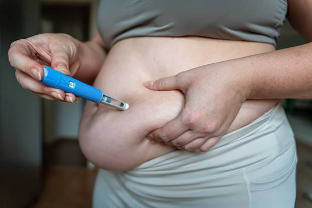Person self-administering a GLP-1 injection pen into the abdomen